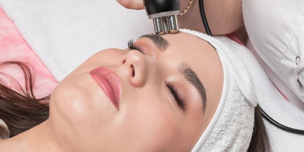 Woman receiving facial treatment with a handheld device at a spa.