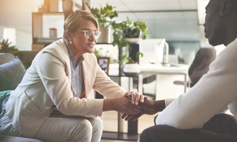 A man talking to a psychologist or therapist. A young african american guy looking sad while getting help during a therapy session with a counsellor