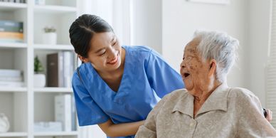 A nurse smiling warmly at an elderly woman in a wheelchair.