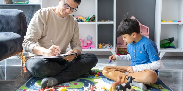 Adult and child playing and drawing together on play mat.