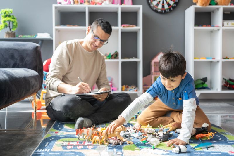 A Professional Child Psychologist Observing Little Boy Playing With Toys At The Psychotherapy Session