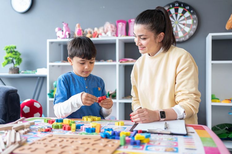 A boy and a woman engage in a playful learning activity with colorful blocks.