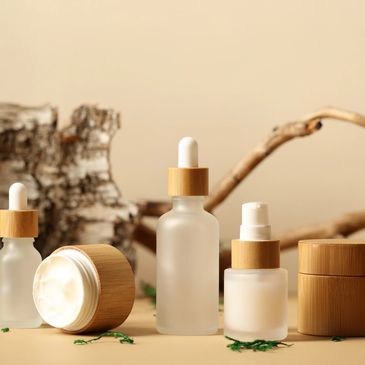 Natural skincare products in frosted glass containers with wooden lids and droppers.