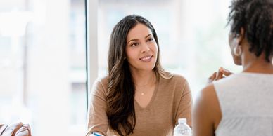 Two women engaged in a conversation during a meeting.