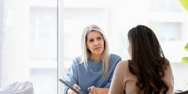 Older woman attentively listening to a younger woman during a meeting.