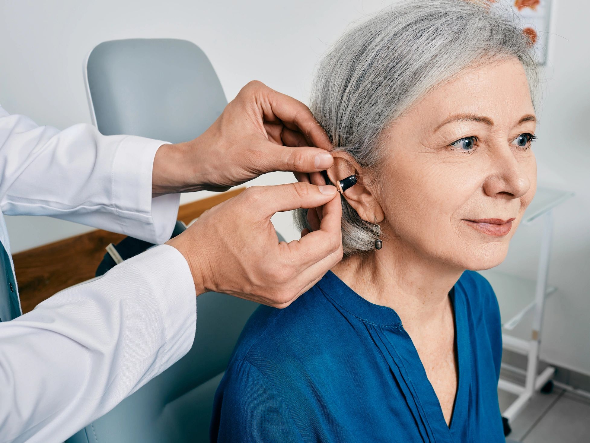 Senior woman getting a hearing aid fitted by a professional.