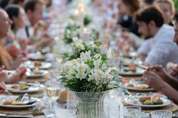Elegant white floral centerpiece on a festive dining table with guests.