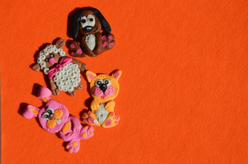 Colorful clay animal figurines on orange background.