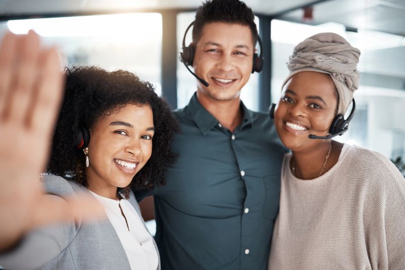 Portrait of a diverse group of happy smiling call centre telemarketing agents taking selfies together in an office. Confident and ambitious colleagues determined to provide the best customer service and sales support