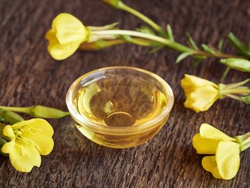 evening primrose flowers surrounding a clear glass bowl with evening primrose oil