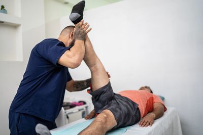 Therapist stretches patient's leg during session.