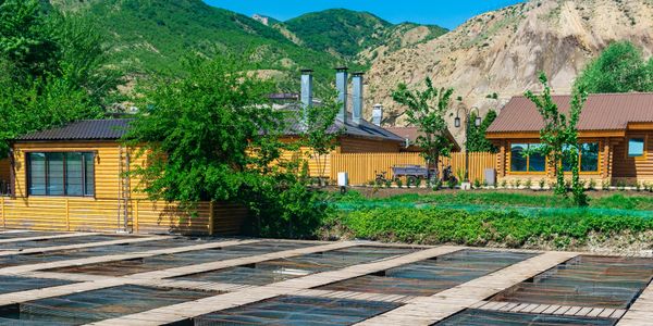 Wooden fish ponds with cabins and mountains in the background.