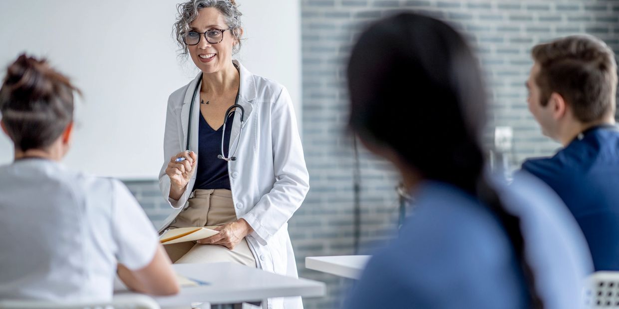 Female doctor engaging with medical students in a classroom setting.