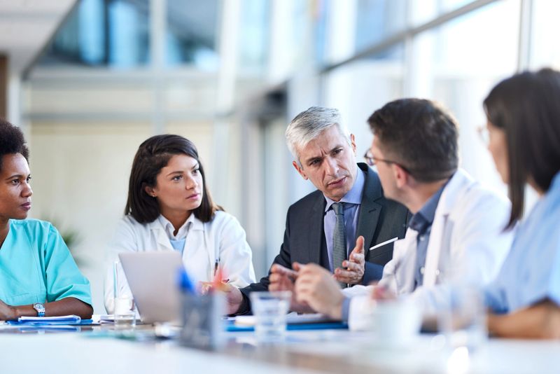 Group of medical experts talking to a businessman while having a business meeting in a hospital.