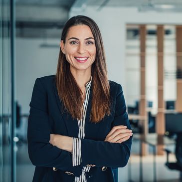 Confident businesswoman smiling with arms crossed in an office.
