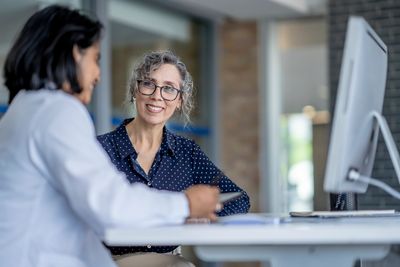 Two women having a friendly conversation in an office setting.