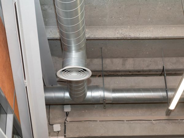 Exposed metal HVAC ducts on a concrete ceiling.