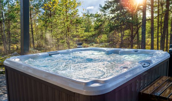 Outdoor hot tub bubbling at sunset in a forest setting.