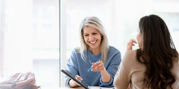 Two women collaborating and smiling indoors.