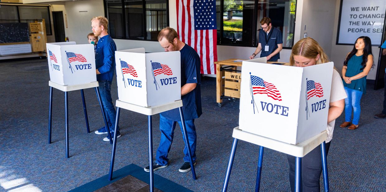 People voting at booths with American flags.