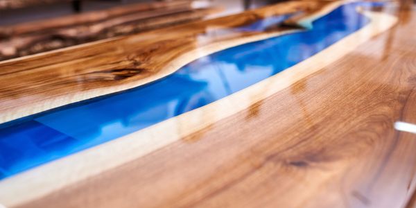 Close-up of a polished wooden table with a blue resin river inlay.