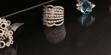 Diamond and blue gemstone rings displayed on a black surface.