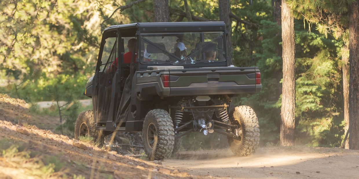 Off-road vehicle carrying four people on a forest trail.