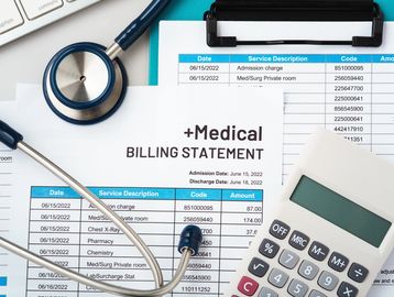 Medical billing statement with stethoscope and calculator on desk.