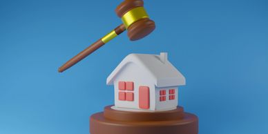 A gavel poised over a model house symbolizing legal decisions in real estate.