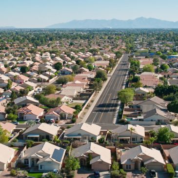 Aerial view of suburban neighborhood with road and mountains.
