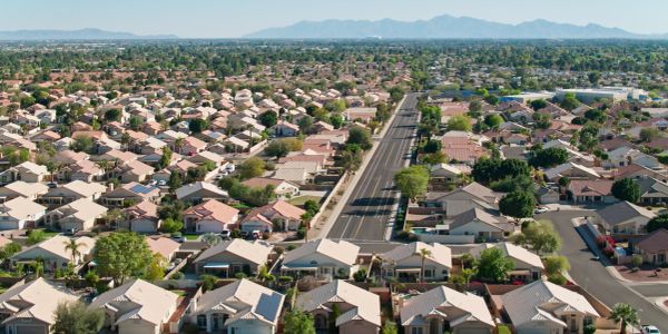 Aerial view of suburban neighborhood with road and mountains.
