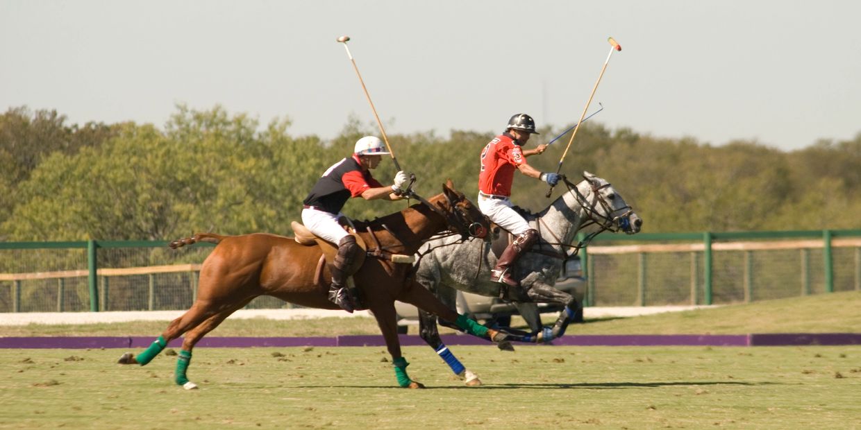 Two players competing fiercely in a polo match on horseback.