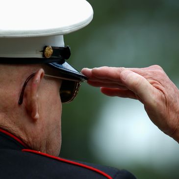 A military personnel saluting with a white cap and black watch.