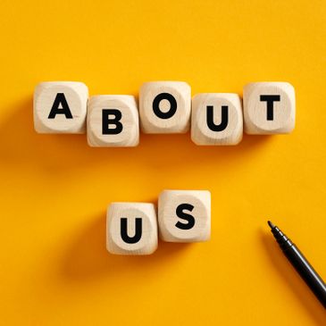 Wooden blocks spell out 'ABOUT US' on a bright yellow background.