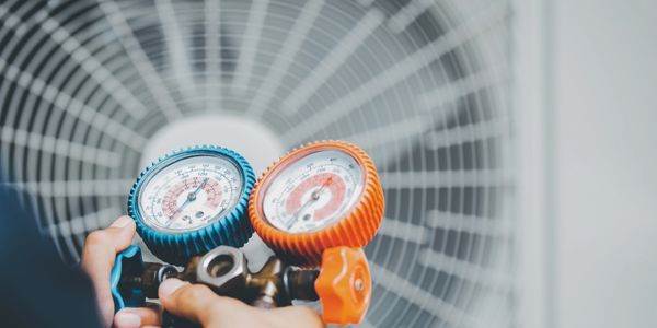 Hands holding HVAC gauge in front of a fan.