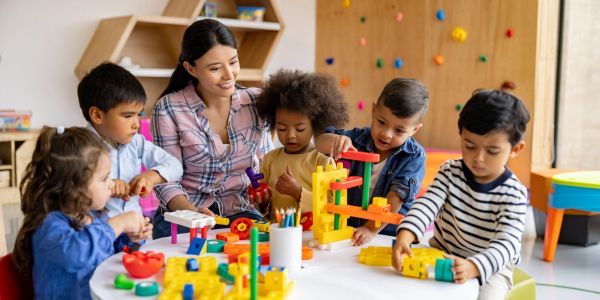 Teacher and kids playing with building blocks in a classroom.