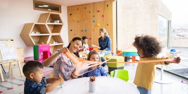Children and teachers play with slime in a classroom.