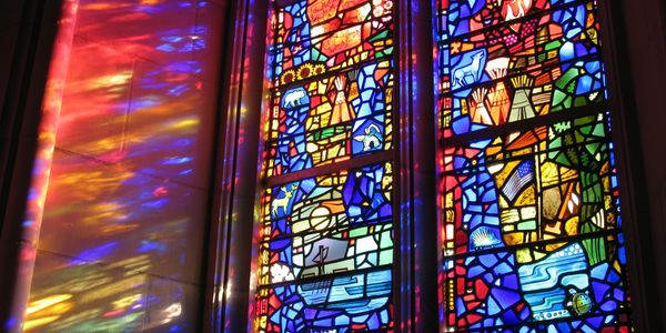 Colorful stained glass window casting vibrant reflections on the wall.