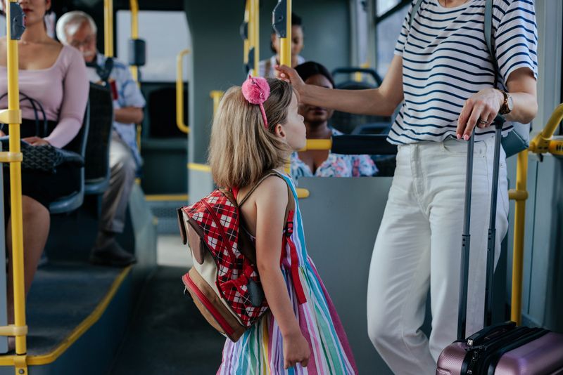 A young little girl and her mom are on the shuttle bus going to the airport