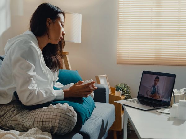 Woman video chatting with a man on a laptop in a cozy living room.