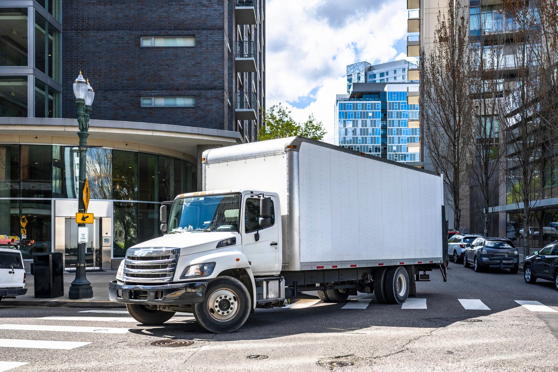 White box truck on a city street corner during the day.