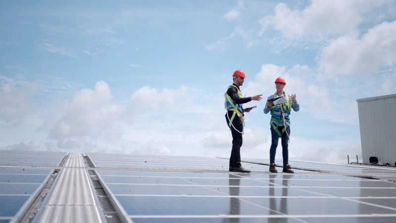 Team industrial engineer or professionals technicians working plant generate electricity from solar energy. Discuss about installing system and maintenance plan of solar panel on the roof of factory.