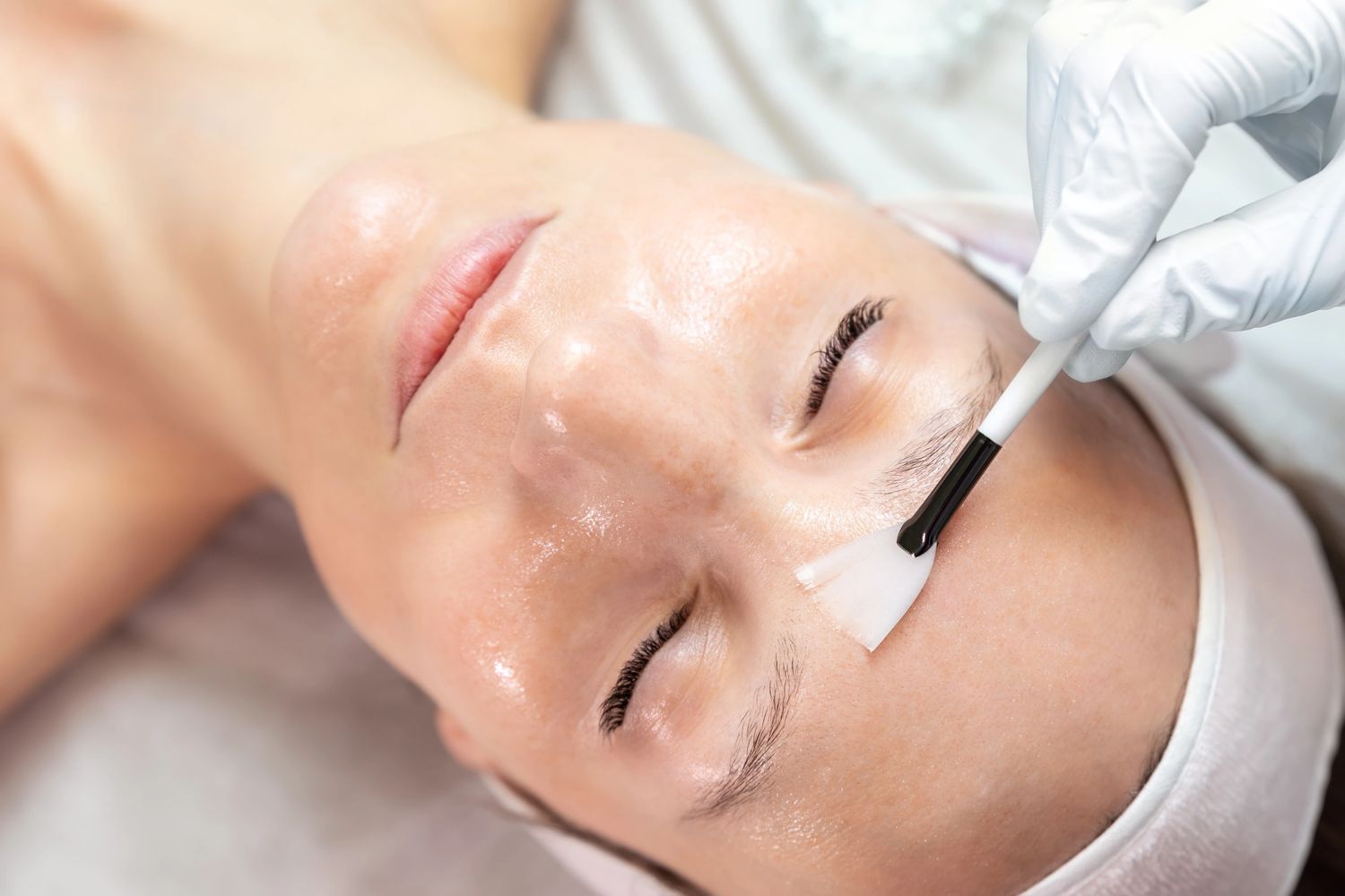 Woman receiving a gentle facial treatment with a brush.