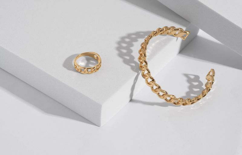 Chain shape modern bracelet and ring on white podium with copy space