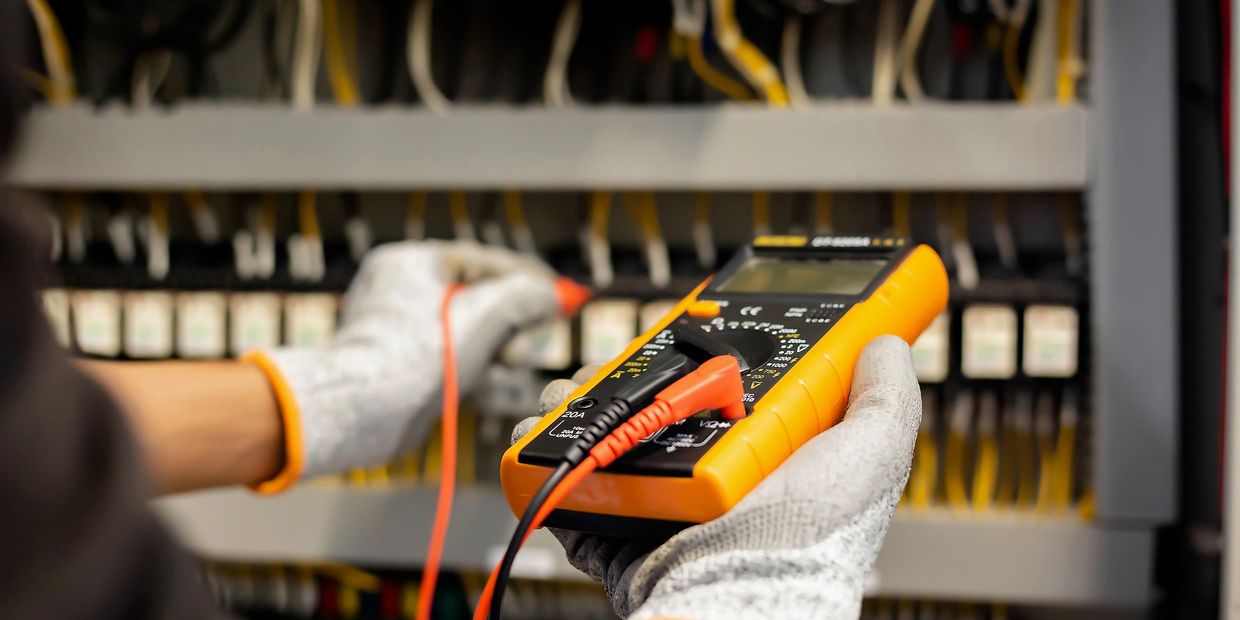 Person using a multimeter to check electrical connections in a panel.