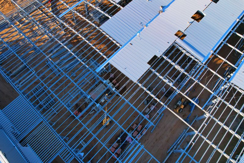 Warehouse Construction from metal structure. Industrial building on light gauge steel framing. Frame of modern hangar or factory. Construction site with steel structure warehouse. Top view on a roof.