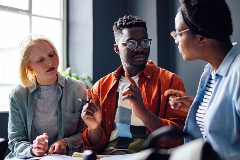 Serious African-American student explains something to his multi ethnic group of friends.