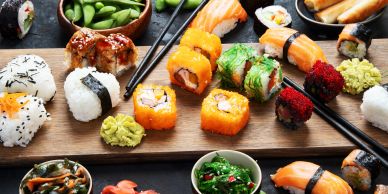 Variety of colorful sushi and sides on a wooden board.