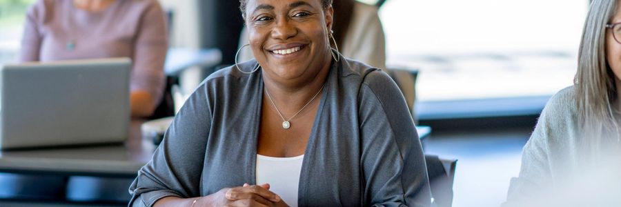 Smiling woman sitting at a desk in a classroom.