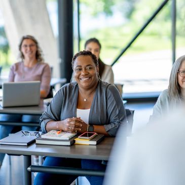 Smiling woman attending a class with others in a bright room.